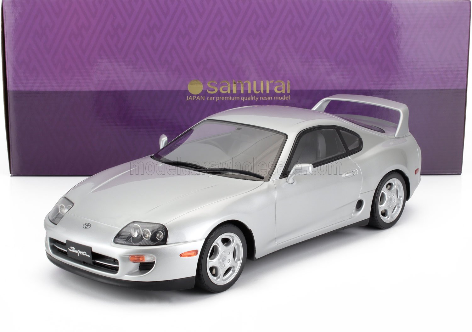 Maqueta de coche Toyota Supra plateado con alerón trasero delante de la caja de resina morada Samurai Japan, disponible en Vroomi.