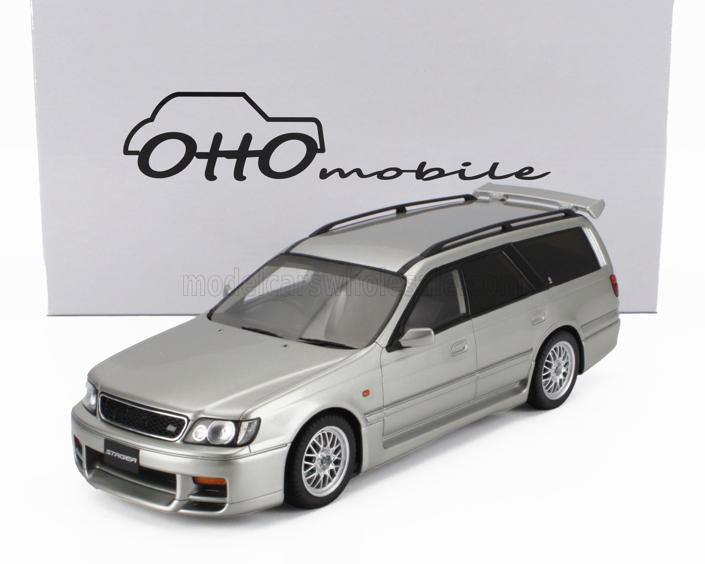 Modelo de coche Nissan Stagea plateado delante del logotipo de Otto Mobile, ahora disponible en la plataforma Vroomi.