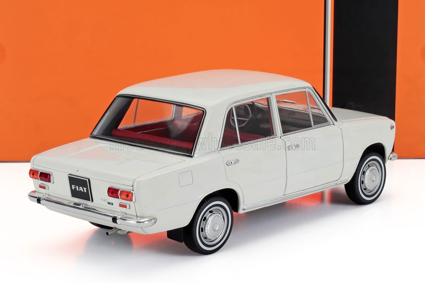 Modelo Fiat sedán vintage blanco con interior rojo sobre superficie blanca, anunciado en la plataforma Vroomi.