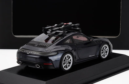 Modelo de coche Porsche 911 Carrera negro con portabicicletas en el techo sobre un expositor, disponible en Vroomi.