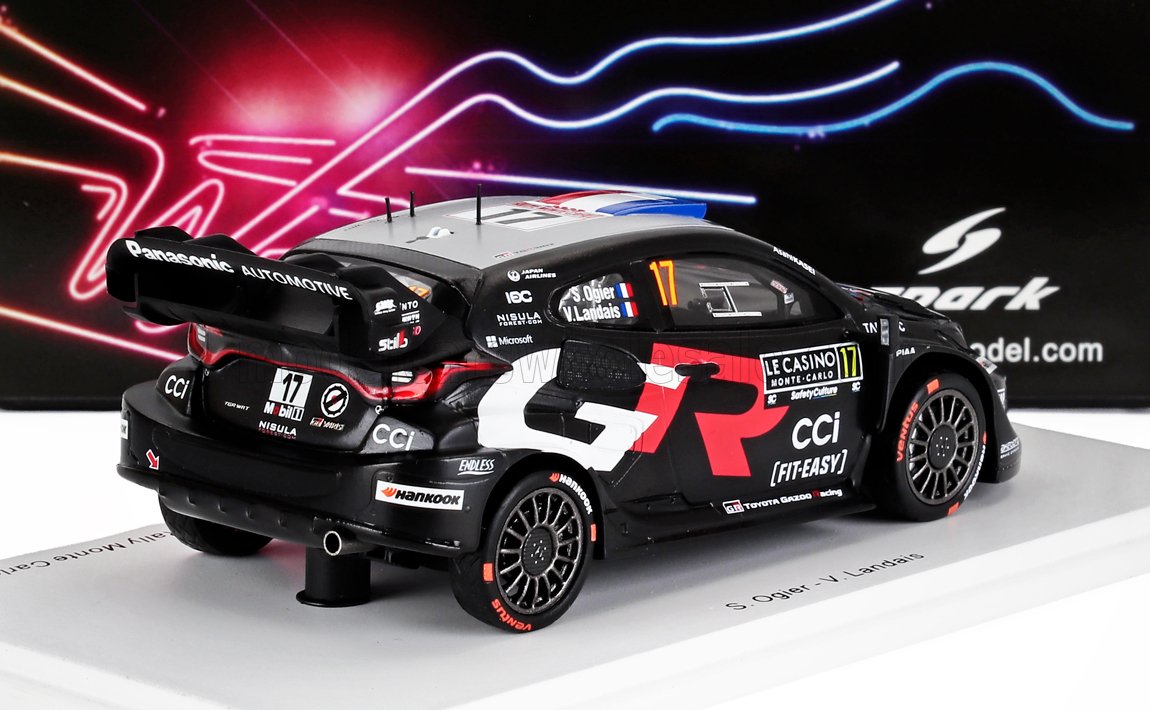 Modelo de coche de rally Toyota GR WRC negro con detalles en rojo, marca Le Casino, expuesto en un soporte blanco, disponible en Vroomi.