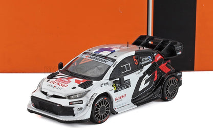 Diecast model of white and black Toyota rally car with sponsor logos, available at Vroomi