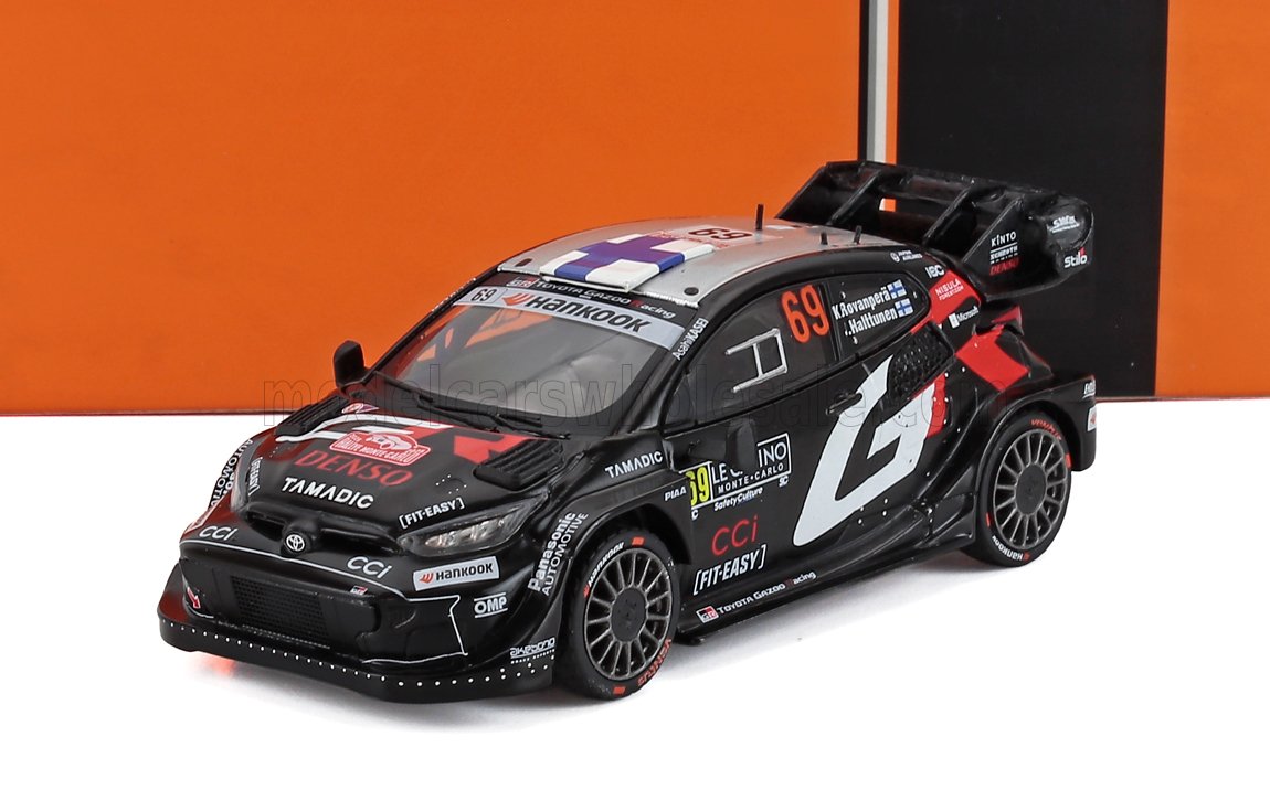 Black Toyota rally car model with number 69 and sponsor logos on white surface, available through Vroomi