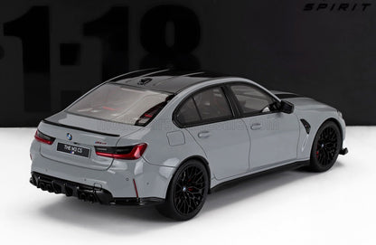 Coche en miniatura BMW M3 CS gris a escala 1/18 con ruedas negras expuesto sobre una superficie blanca, disponible en Vroomi.