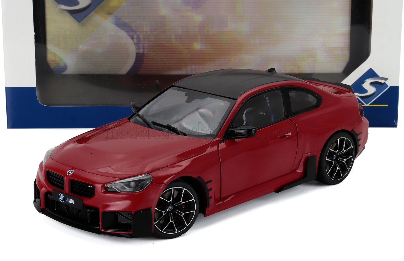 Coche de juguete BMW M2 rojo con techo negro y llantas detalladas, disponible a través de Vroomi.
