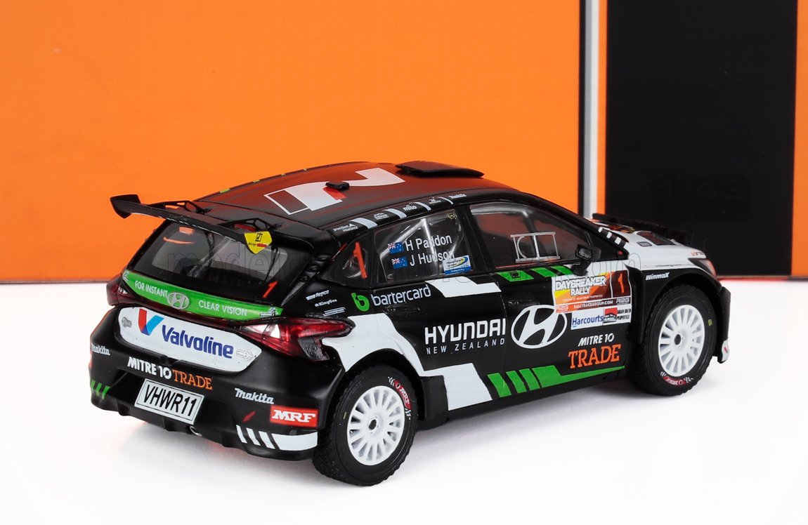 Modelo de coche de rally Hyundai Zelanda en blanco y negro con adhesivos de patrocinadores, disponible en el mercado Vroomi.