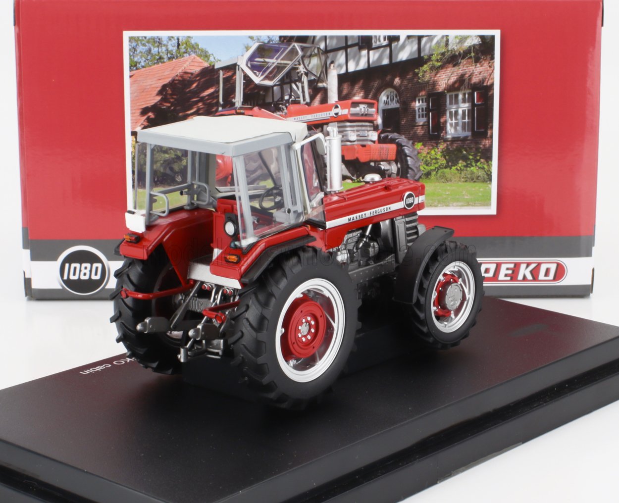 Maqueta detallada a escala de un tractor Massey Ferguson 1080 rojo con capota blanca, expuesta sobre una plataforma negra con el embalaje al fondo, disponible a través de Vroomi.
