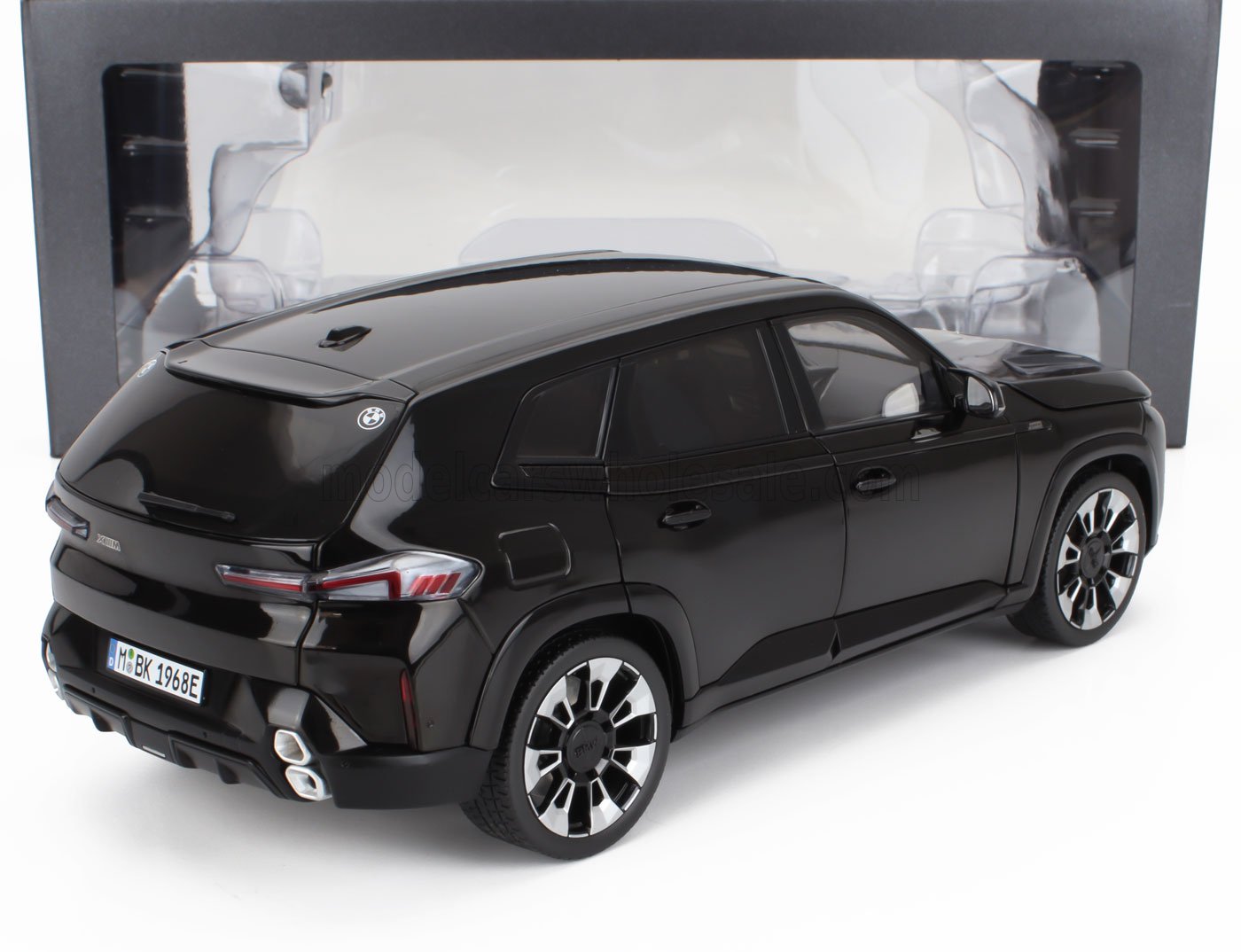 Vista trasera del modelo de coche BMW XM negro con ruedas detalladas y matrícula, disponible en Vroomi.