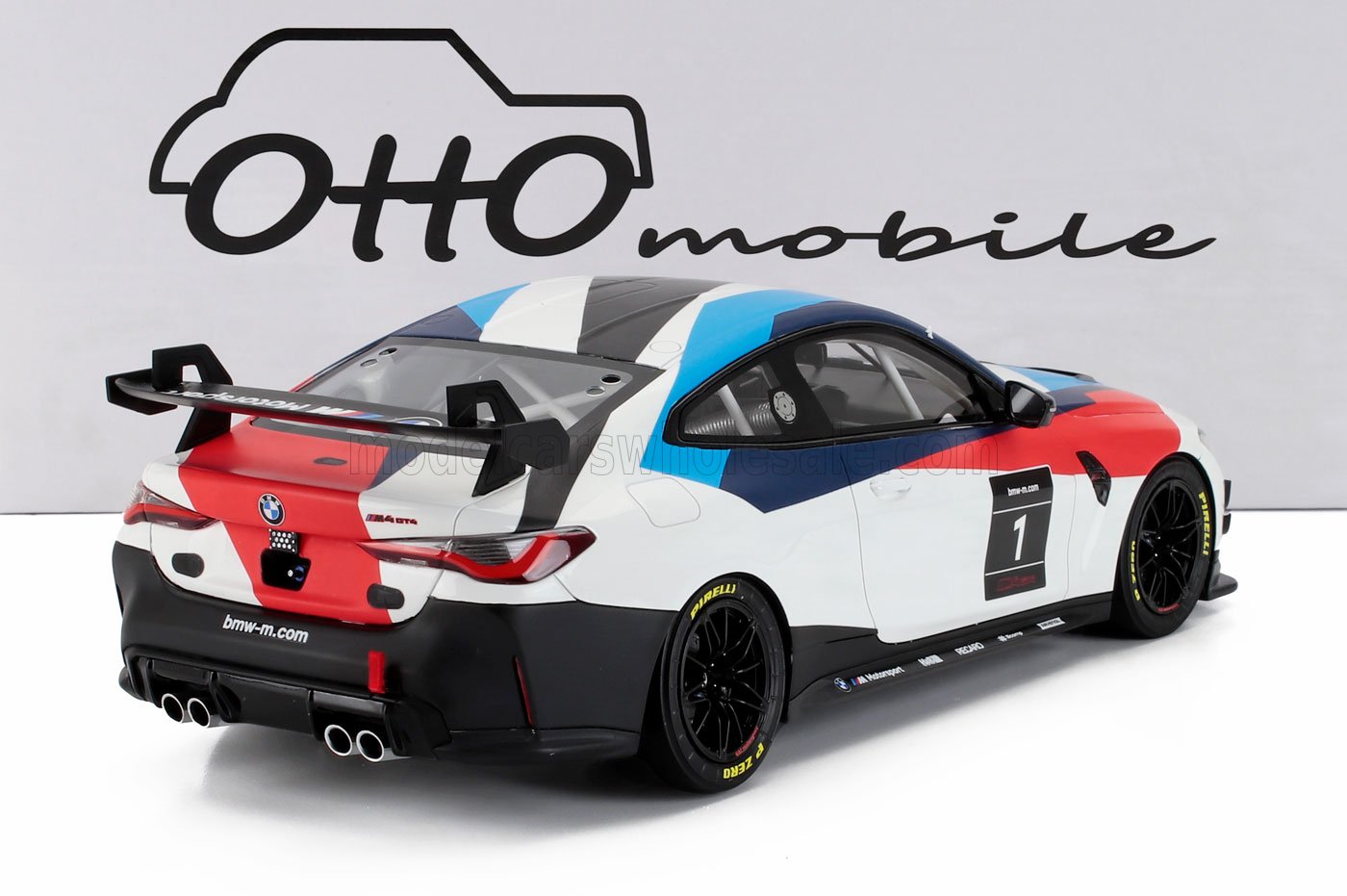 Modelo de coche de carreras BMW M4 GT4 con decoración roja, blanca y azul y gran alerón trasero, anunciado en Vroomi.