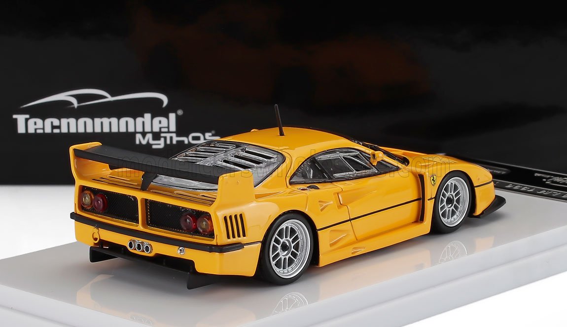 Maqueta a escala de un Ferrari F40 amarillo con alerón trasero en soporte de exposición, disponible a través de la plataforma Vroomi.