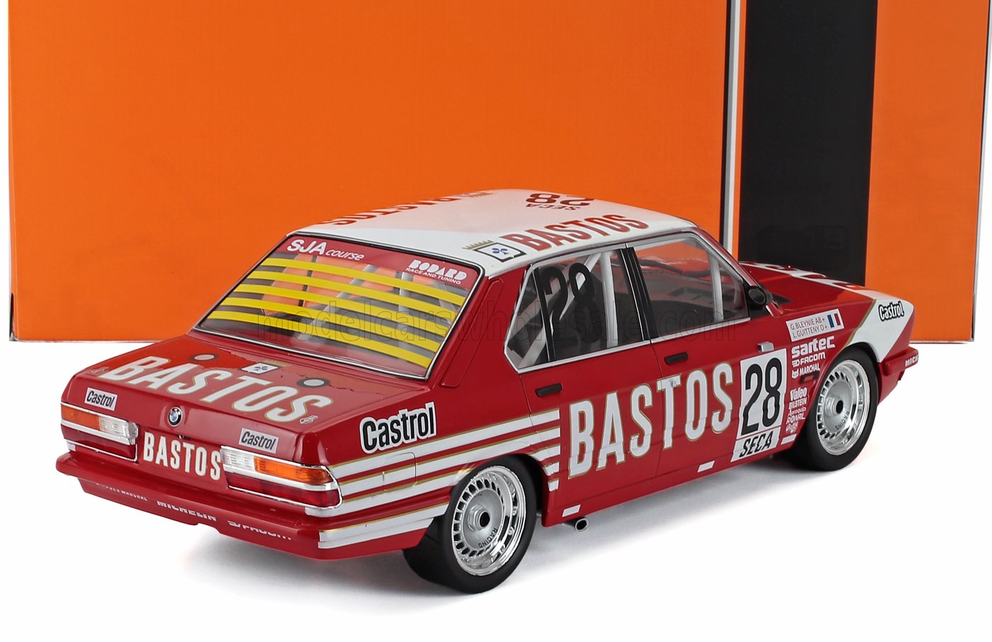 Coche de carreras BMW Bastos rojo y blanco con el número 28 y logotipos de Castrol, expuesto en Vroomi.