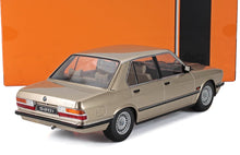 Modelo detallado del BMW 520i dorado con vista trasera y lateral, mostrado con una caja naranja y negra, también disponible en Vroomi.