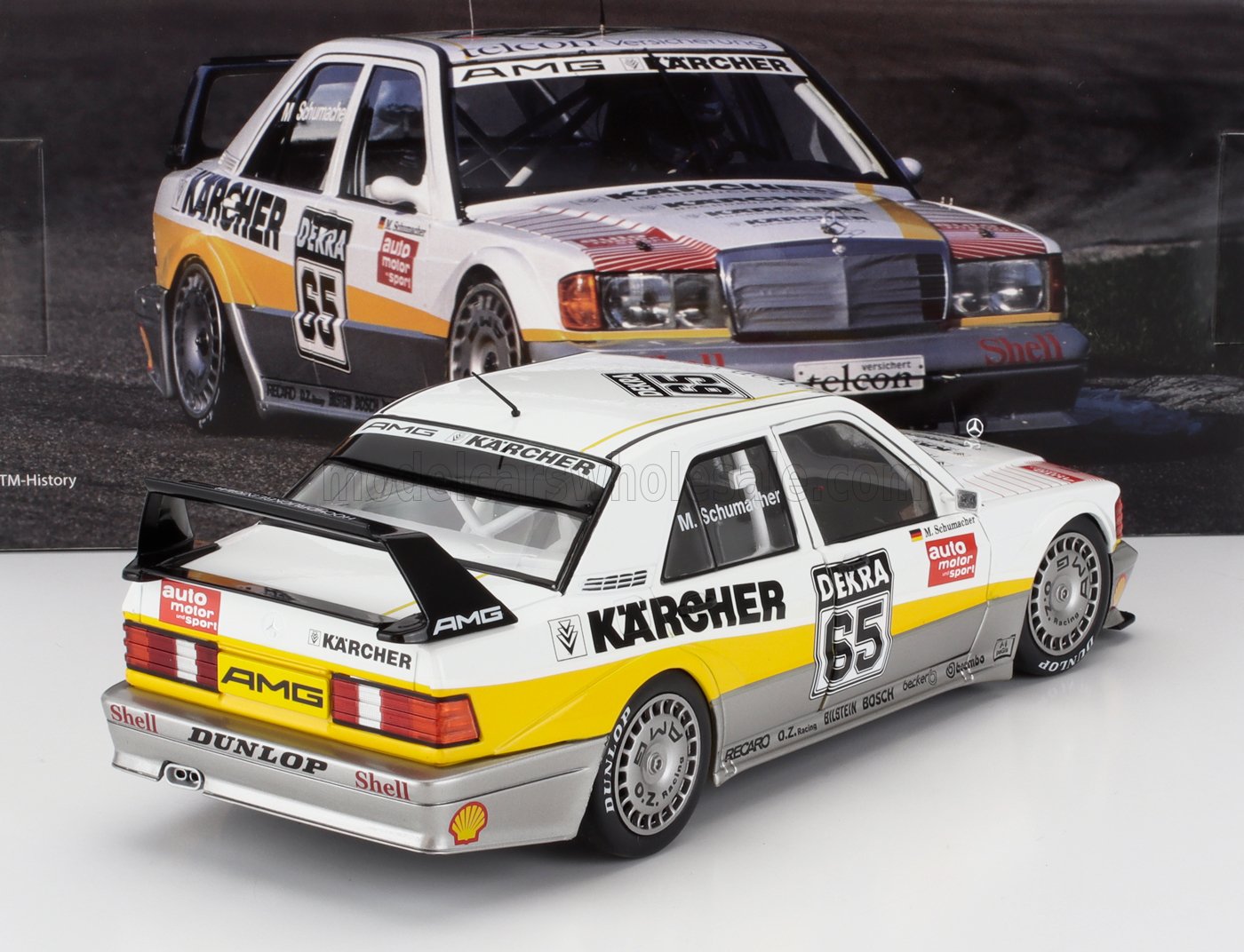 Modelo de coche de carreras Mercedes AMG DTM blanco y amarillo con los logotipos de Karcher y Dunlop, expuesto en una vitrina; ahora aparece en Vroomi.