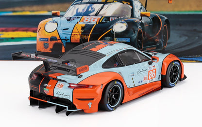 Porsche 911 RSR race car model in blue and orange, displayed with racing backdrop, available on Vroomi