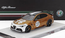 Modelo de coche Alfa Romeo en bronce y blanco con el número 227, expuesto en una plataforma, disponible en Vroomi.