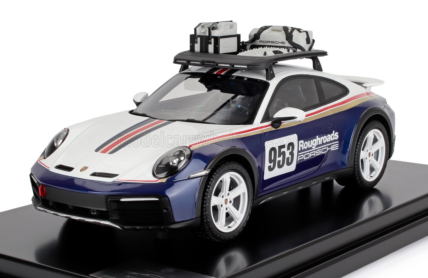 Modelo de coche de rally Porsche 953 Roughroads con carrocería blanca y azul, portaequipajes con equipamiento, disponible en Vroomi.