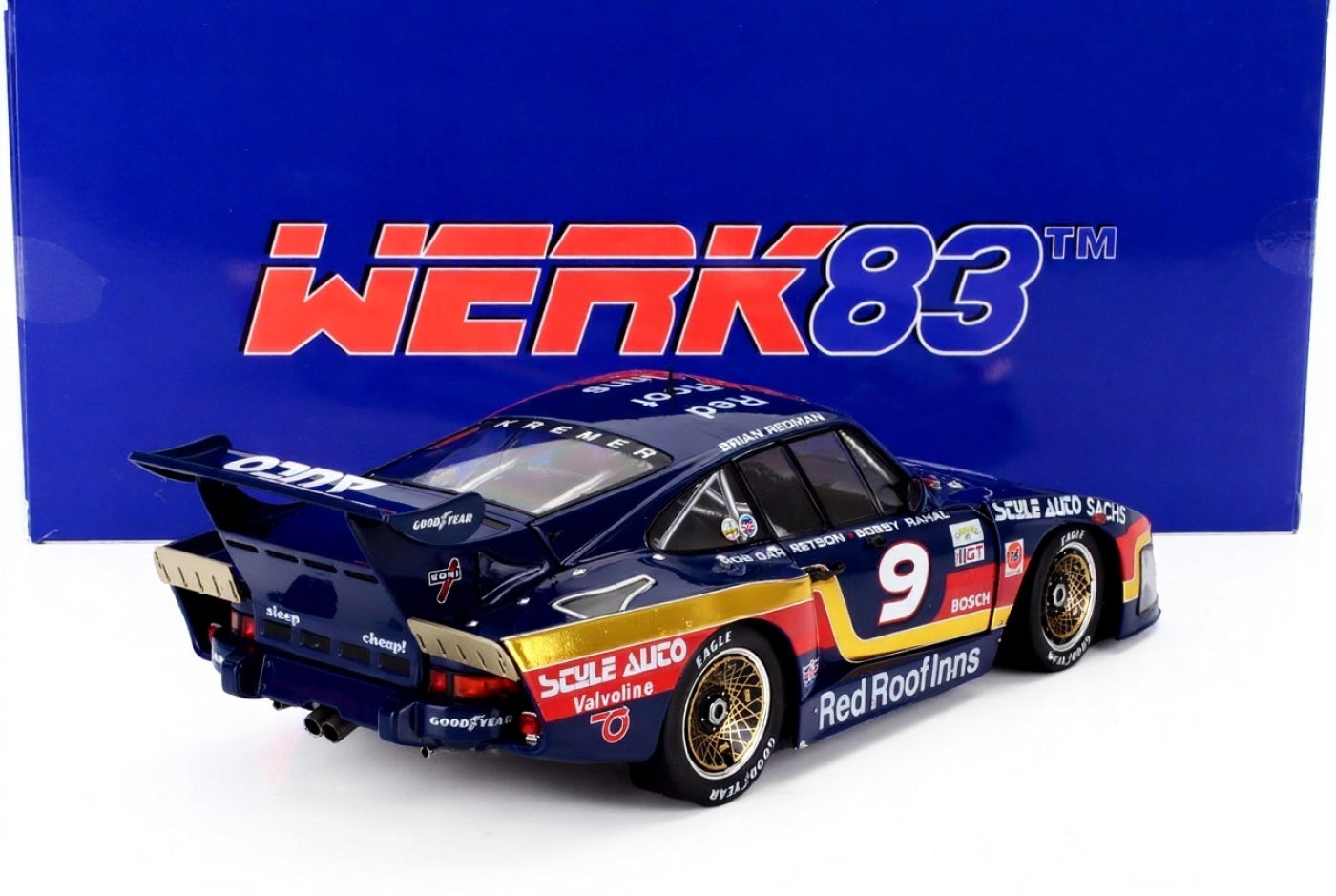 Dark blue Porsche race car model with Red Roof Inns branding and gold accents, shown with Werk83 box, available on Vroomi