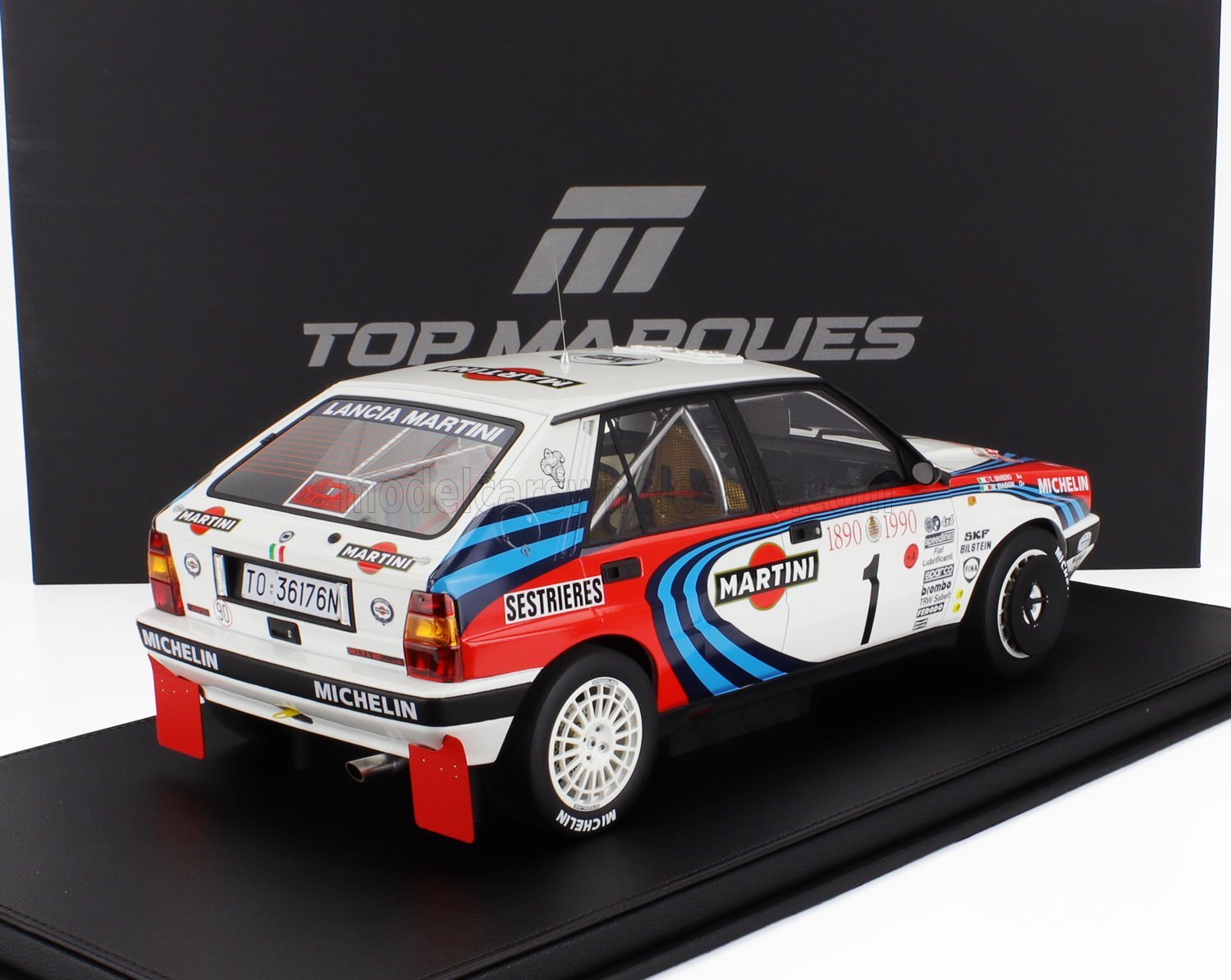 Modèle réduit de voiture de course Lancia Delta Integrale Martini avec autocollants des sponsors sur présentoir noir Top Marques, proposé sur Vroomi.