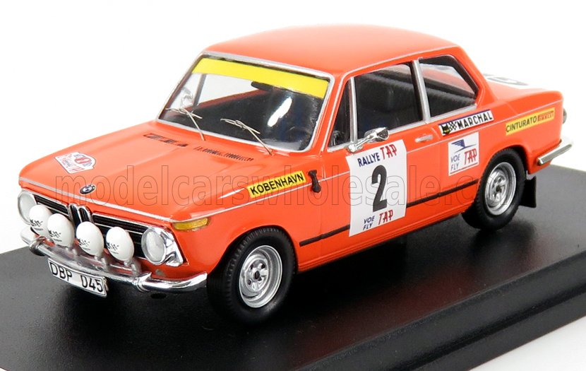 Modèle réduit vintage orange d'une voiture de rallye BMW avec autocollants des sponsors sur socle d'exposition, désormais disponible sur Vroomi.