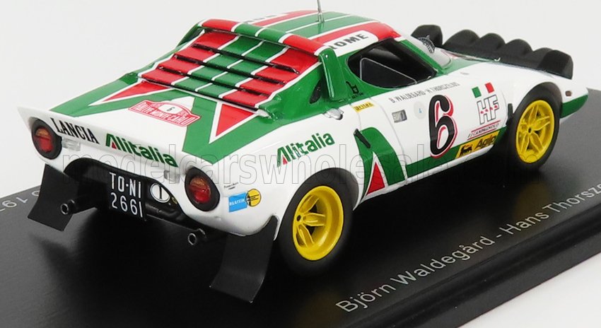 Modèle réduit de voiture de rallye Lancia Stratos aux couleurs d'Alitalia, avec roues jaunes, présenté sur un socle d'exposition, disponible sur Vroomi.