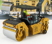 Modèle réduit moulé sous pression d'un rouleau compresseur tandem CAT CB13 avec figurine d'opérateur, disponible sur la plateforme Vroomi.