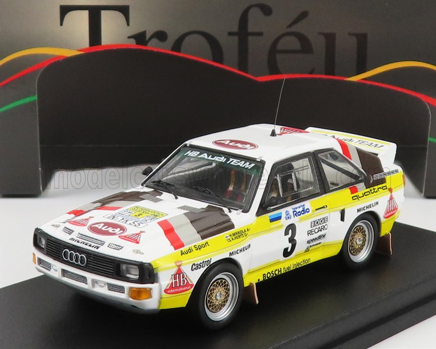 Maquette réduite d'une Audi Quattro blanche de rallye aux couleurs de l'équipe HB Audi, disponible sur Vroomi.