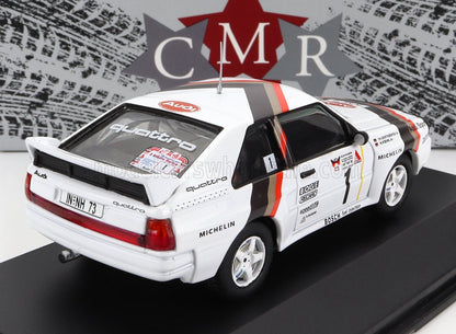 Modèle réduit de voiture de rallye Audi Quattro blanche avec décalcomanies de course, logos des sponsors et numéro 1, disponible sur Vroomi.