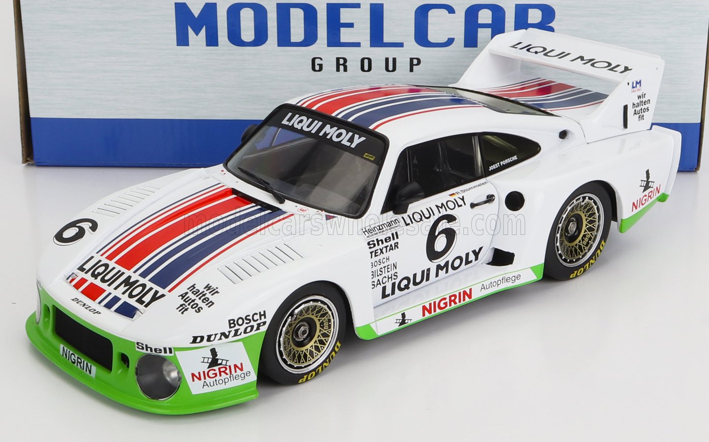 Modèle réduit de voiture de course Porsche blanche à l'échelle 1/18 avec autocollants des sponsors Liqui Moly et Nigrin, disponible chez Vroomi.