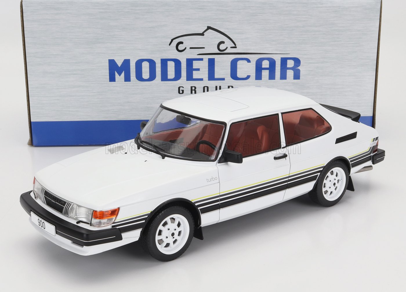 Modèle réduit de voiture Saab 900 turbo blanche avec bandes noires et intérieur rouge, présenté dans une boîte Model Car Group, disponible chez Vroomi.
