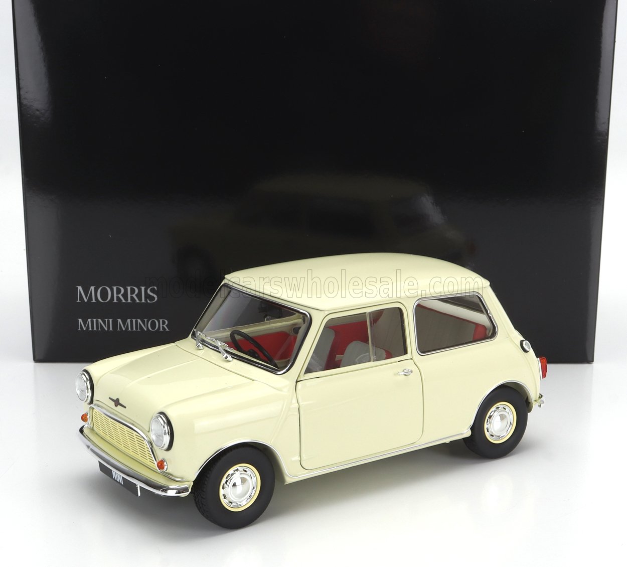 Modèle réduit Cream Morris Mini Minor avec intérieur rouge exposé devant une boîte noire, désormais disponible sur Vroomi.