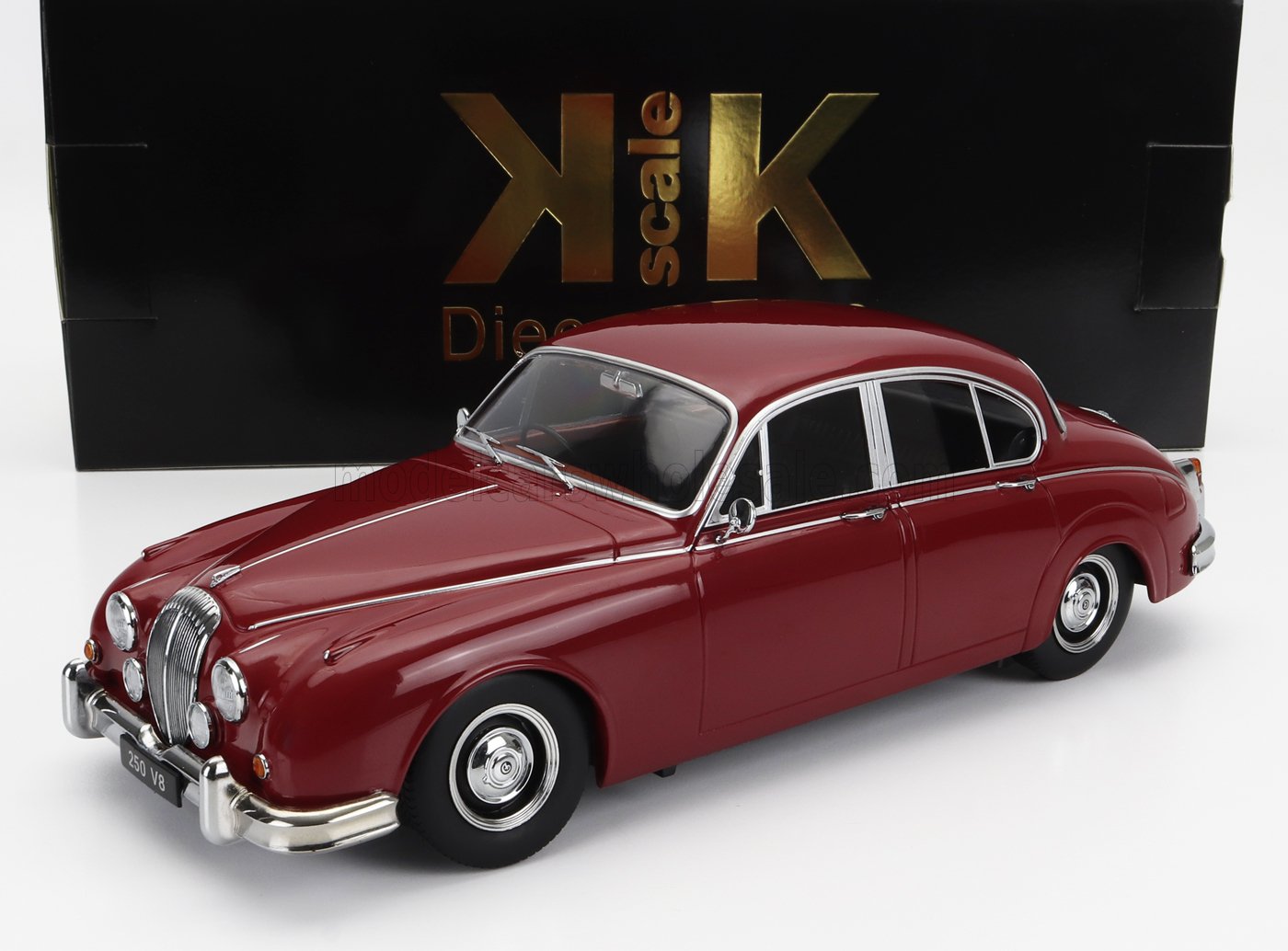 Modèle réduit Jaguar V8 classique rouge avec détails chromés sur fond blanc, disponible chez Vroomi.