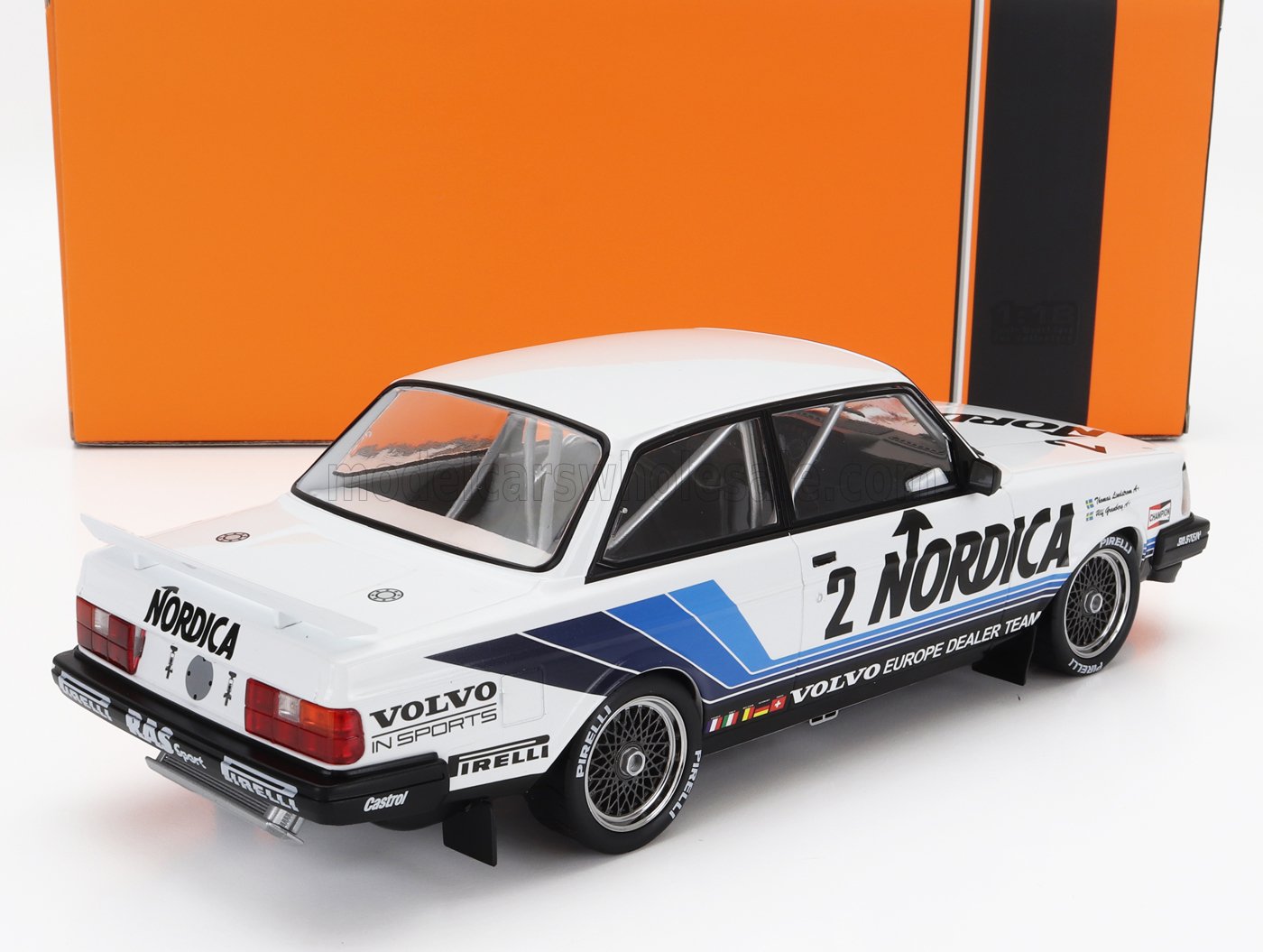 Modèle réduit de voiture de course Volvo blanche avec livrée Nordica, bandes bleues, pneus Pirelli, présenté sur un socle orange, disponible sur Vroomi.