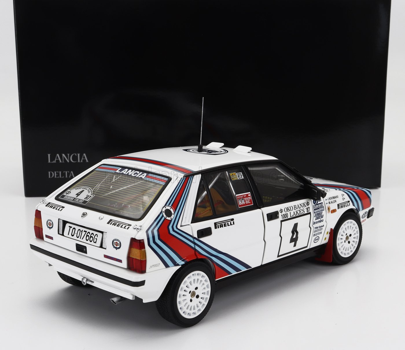 Modèle réduit de voiture de rallye Lancia Delta blanche avec bandes Martini, autocollants des sponsors et numéro 4, proposé sur Vroomi.
