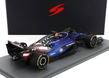 Modèle réduit en métal moulé sous pression d'une voiture de course de Formule 1 bleue arborant le drapeau américain et le numéro 23, présenté sur un socle gris, disponible sur Vroomi.