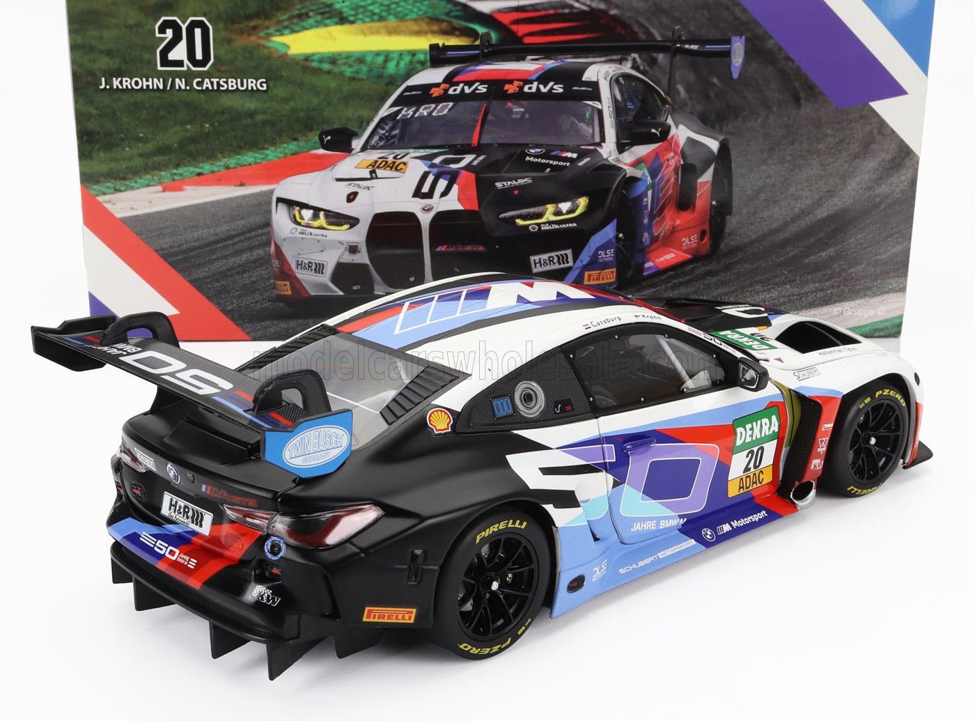 Modèle réduit de voiture de course BMW M4 GT3 avec livrée colorée et autocollants des sponsors, présenté sur la plateforme Vroomi.