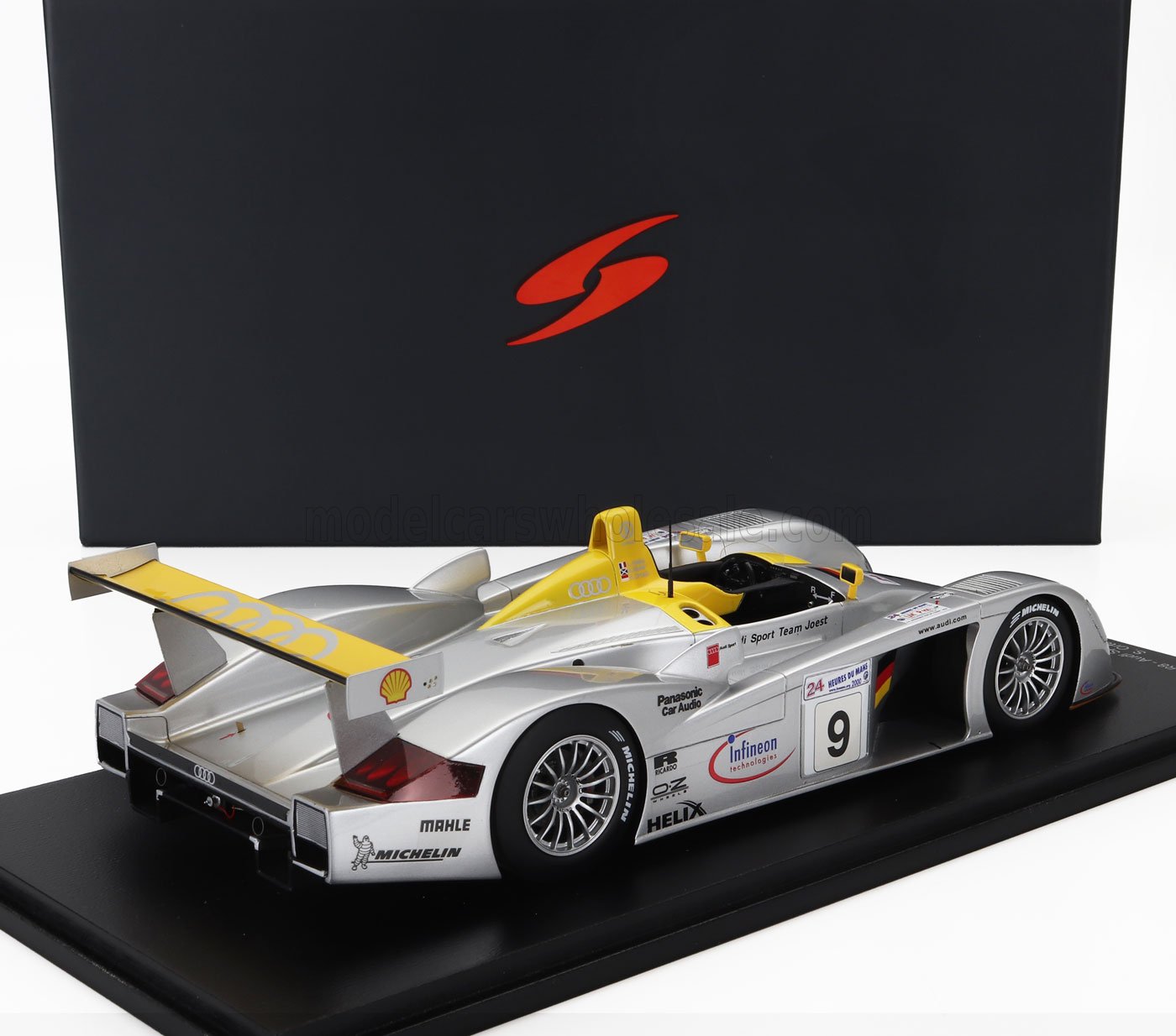 Modèle réduit de voiture de course Audi Sport Team Joest argent et jaune sur socle d'exposition, disponible via Vroomi
