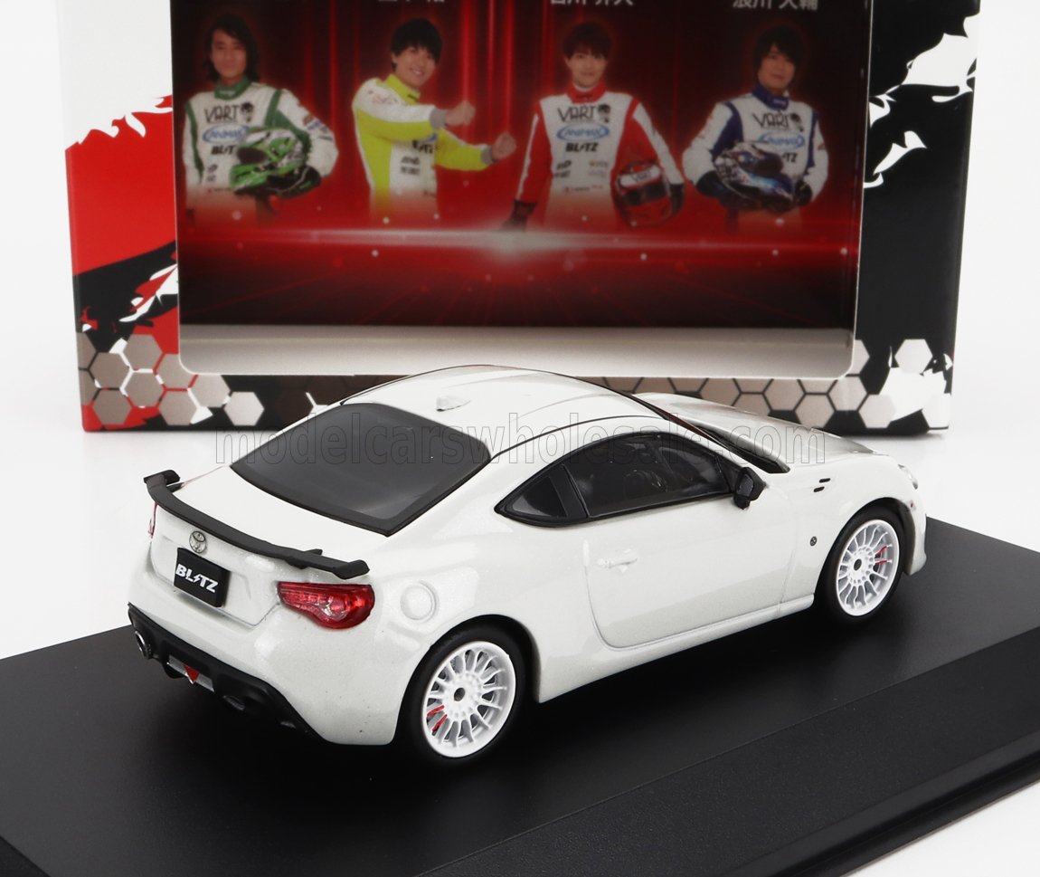Modèle réduit Toyota 86 blanc avec spoiler arrière noir sur socle d'exposition, proposé via la plateforme Vroomi.