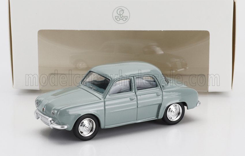 Modèle réduit de voiture vintage gris clair devant une vitrine blanche, disponible sur la plateforme Vroomi.