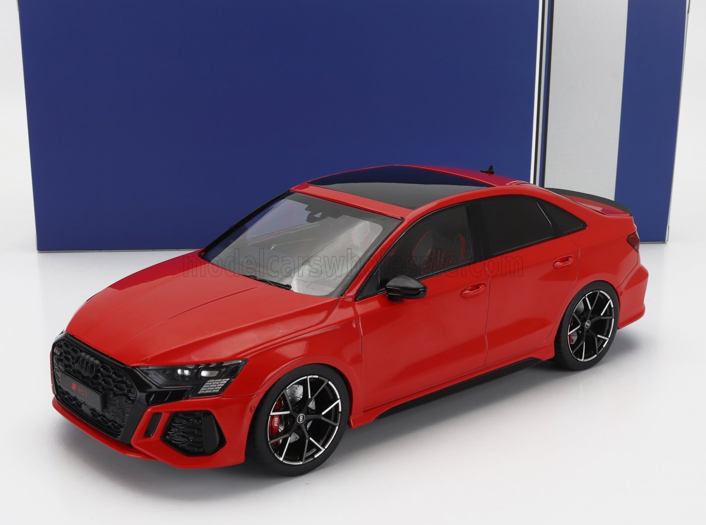 Modèle réduit de voiture Audi RS3 rouge avec détails noirs et jantes en alliage, présenté dans un emballage bleu disponible chez Vroomi.
