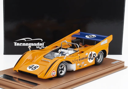 Modèle réduit Technomodel à l'échelle 1:18 d'une voiture de course McLaren orange numéro 48 avec spoiler bleu, présenté sur un socle beige, proposé sur Vroomi.