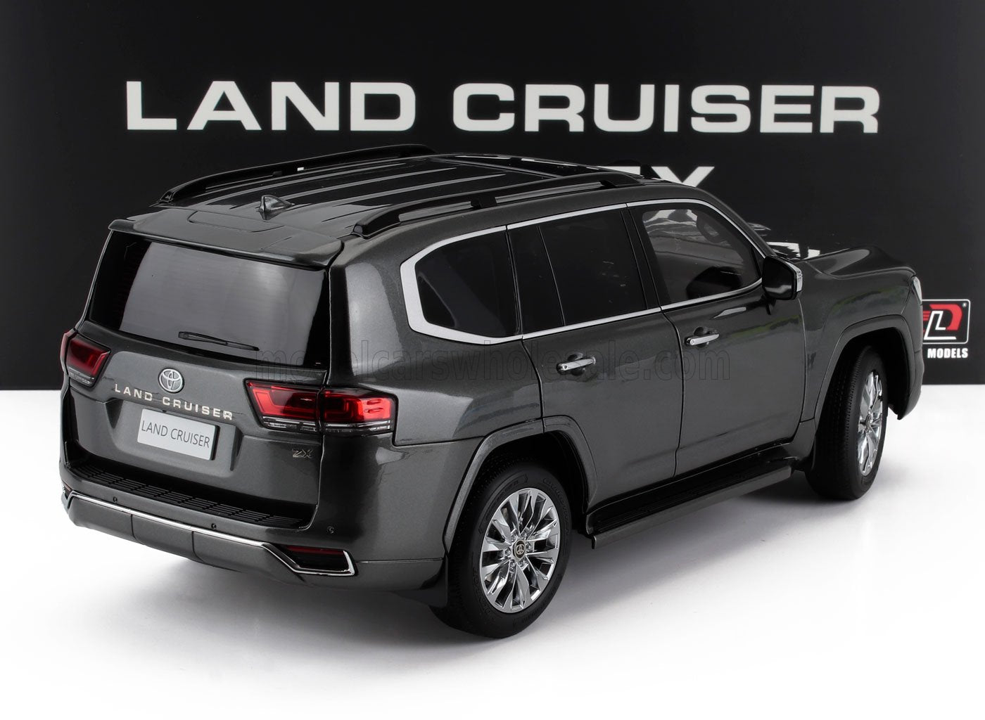 SUV Toyota Land Cruiser ZX gris foncé sur fond blanc avec logo Land Cruiser, proposé sur Vroomi.