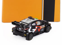 Modèle réduit d'une voiture de rallye Toyota noire et argentée avec des accents rouges et un aileron, référencé sur Vroomi.