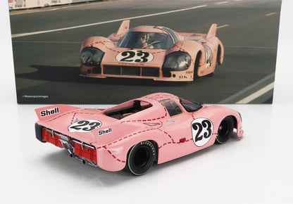 Modèle réduit de voiture de course Porsche 917 rose avec le numéro 23 et les logos Shell, accompagné d'une photo de course vintage, désormais disponible sur Vroomi.