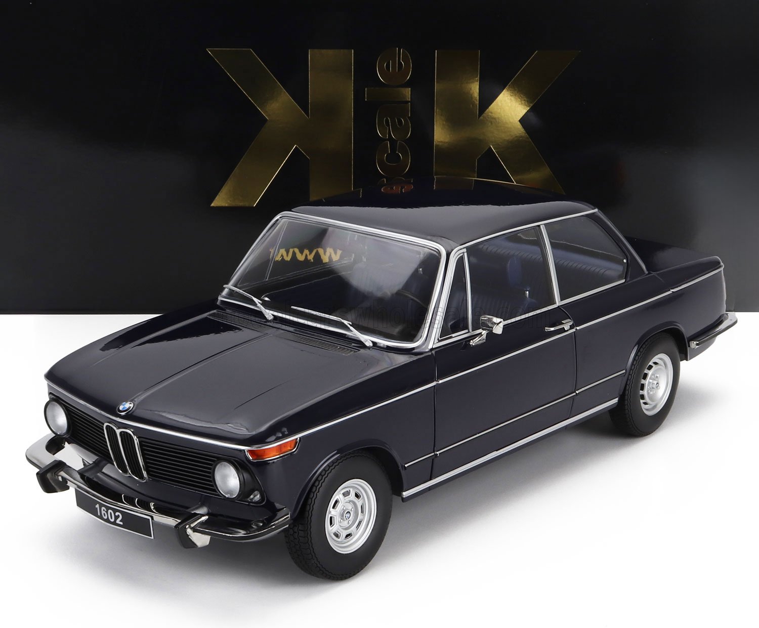 Modèle classique de berline BMW 1602 noire avec garnitures chromées, présenté sur un fond noir et or à l'échelle K, disponible sur Vroomi.