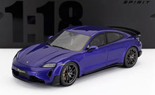 Maquette d'une Porsche Taycan bleu métallisé avec des roues noires, exposée sur une surface blanche, disponible chez Vroomi.