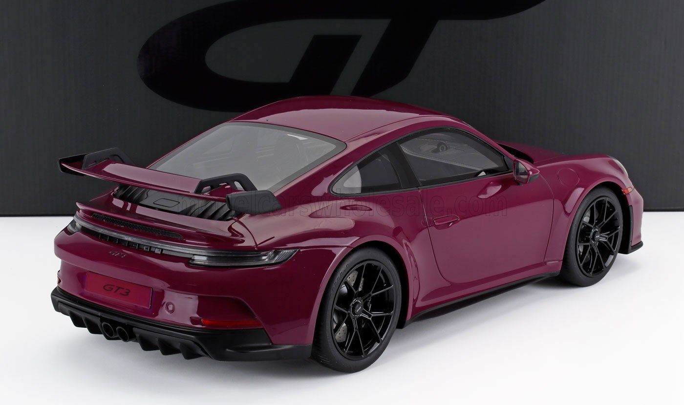 Gros plan sur une maquette de Porsche 911 GT3 à l'échelle 1/18 de couleur bordeaux avec des roues noires, présentée sur Vroomi.