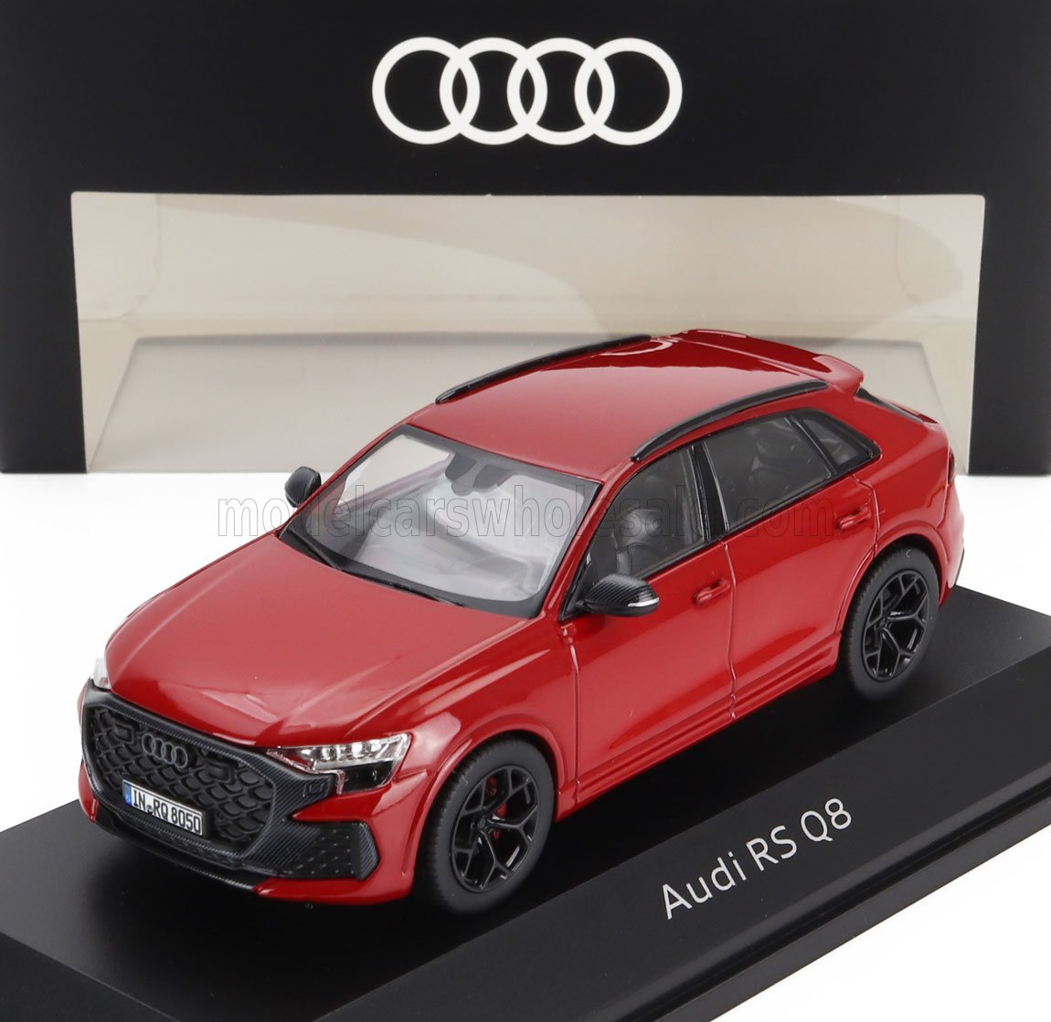 Modèle réduit Audi RS Q8 rouge sur présentoir avec roues noires, fond avec logo Audi, disponible via Vroomi