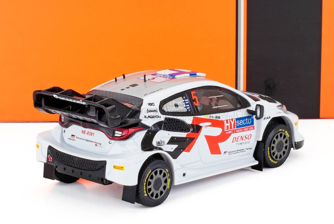 Modèle réduit blanc de voiture de rallye Toyota Gazoo Racing avec spoilers et autocollants des sponsors, présenté sur Vroomi.