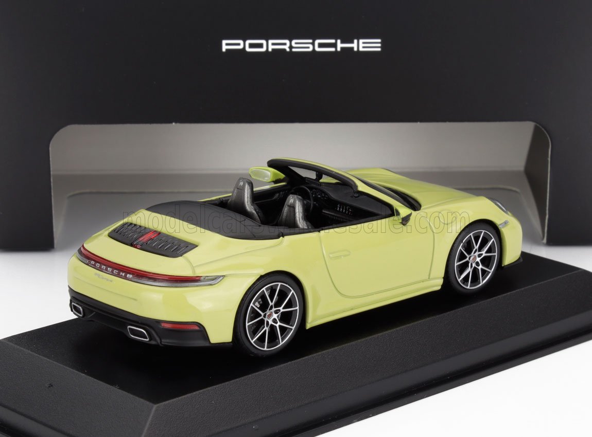 Modèle réduit jaune Porsche 911 Cabriolet sur socle avec logo Porsche, présenté sur Vroomi.