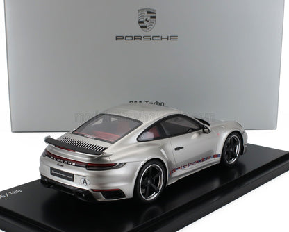 Modèle réduit Porsche 911 Turbo argenté sur socle d'exposition avec boîte Porsche en arrière-plan, disponible via Vroomi.
